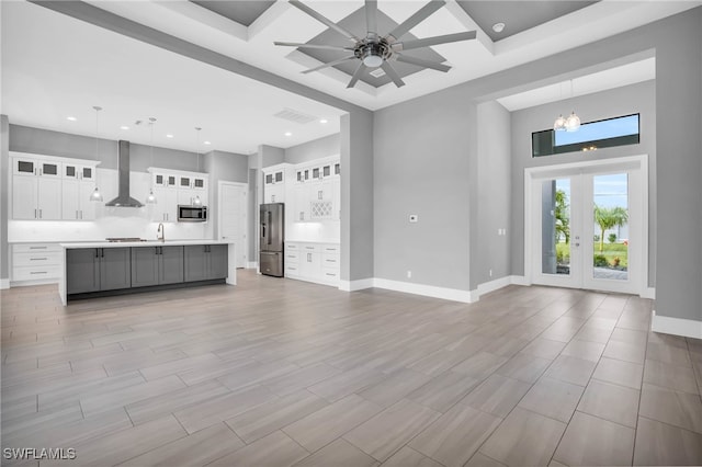 unfurnished living room with french doors, sink, light hardwood / wood-style flooring, and ceiling fan with notable chandelier