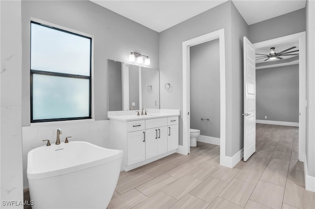 bathroom with a tub to relax in, vanity, toilet, and ceiling fan