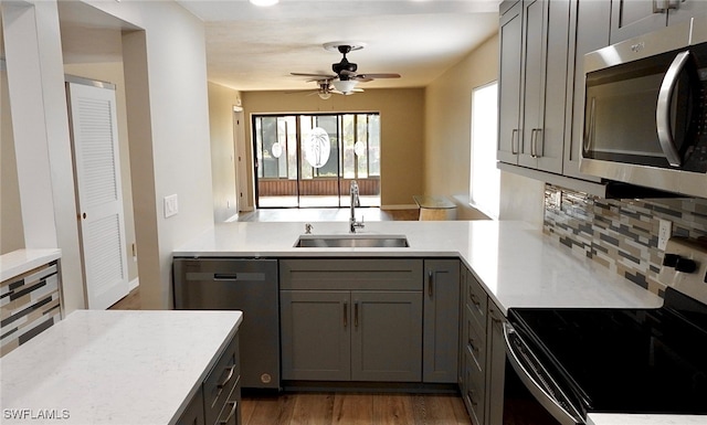 kitchen featuring backsplash, appliances with stainless steel finishes, dark hardwood / wood-style floors, gray cabinets, and sink