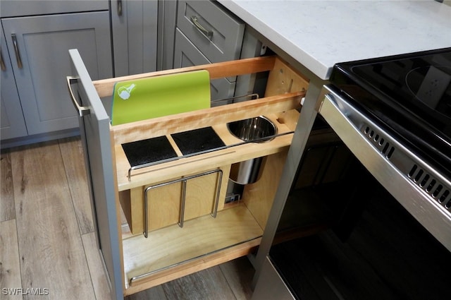 room details featuring hardwood / wood-style floors, stainless steel electric stove, and gray cabinetry