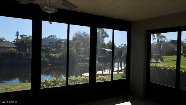 unfurnished sunroom featuring a water view and ceiling fan