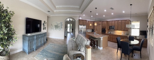 kitchen with a large island with sink, decorative light fixtures, a kitchen bar, decorative backsplash, and appliances with stainless steel finishes