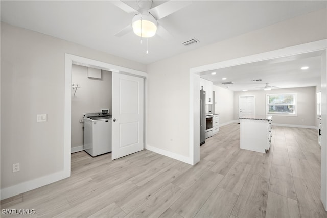 unfurnished living room with light hardwood / wood-style floors, ceiling fan, and washer / clothes dryer