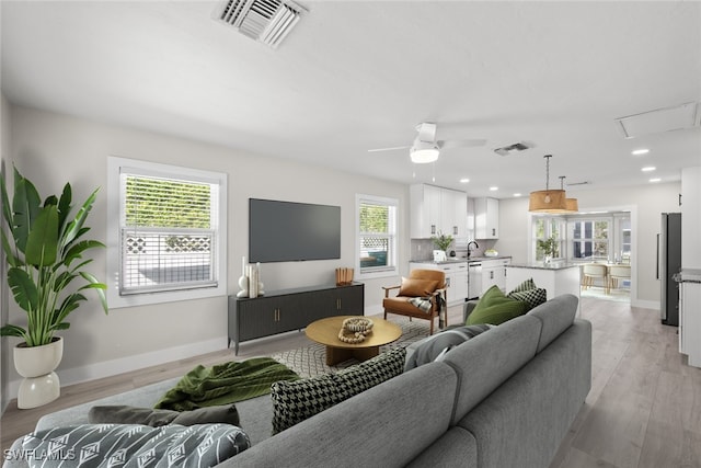 living room with light wood-type flooring, sink, and ceiling fan