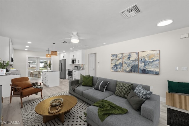 living room with light wood-type flooring and ceiling fan