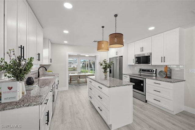 kitchen featuring appliances with stainless steel finishes, a sink, baseboards, tasteful backsplash, and a kitchen island