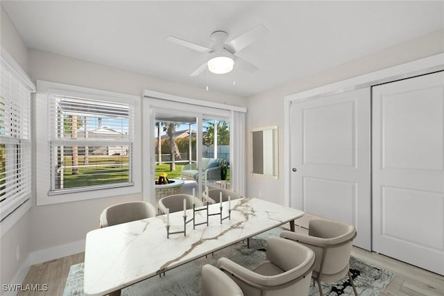 dining space with a ceiling fan, light wood-style floors, and baseboards