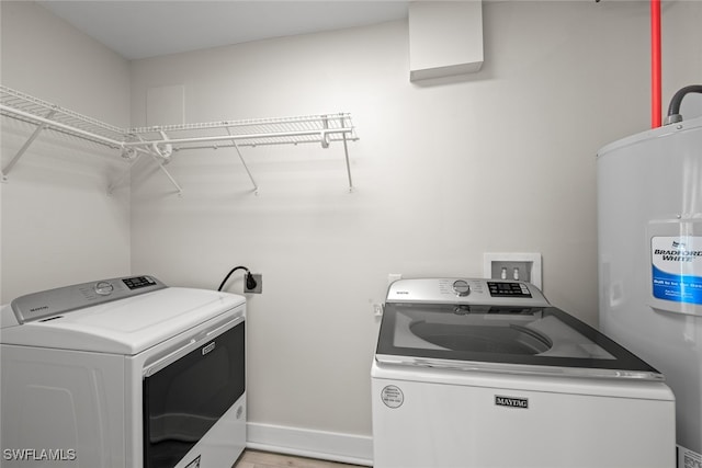 clothes washing area with washing machine and clothes dryer and water heater