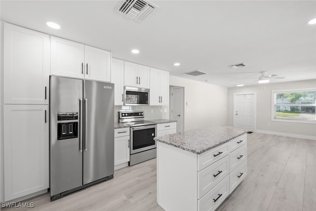 kitchen featuring white cabinetry, appliances with stainless steel finishes, light stone counters, and light hardwood / wood-style flooring