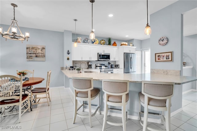 kitchen with white cabinetry, kitchen peninsula, appliances with stainless steel finishes, and sink