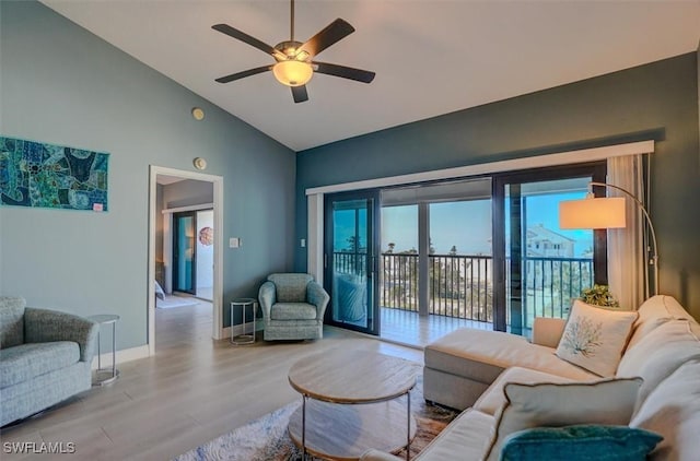 living room with ceiling fan, light hardwood / wood-style floors, and vaulted ceiling