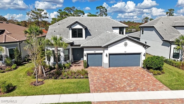 view of front facade featuring a garage, decorative driveway, a tiled roof, and a front lawn