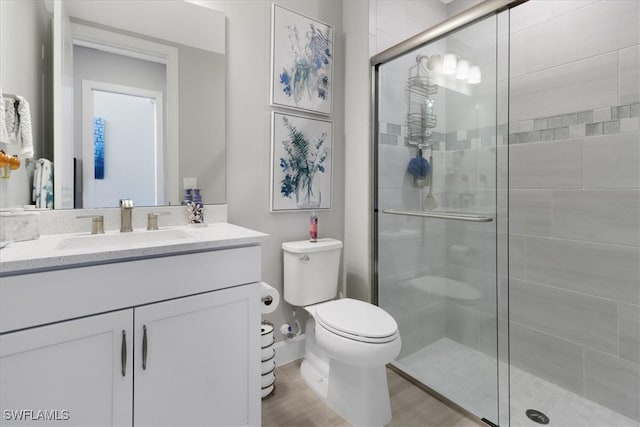 bathroom with toilet, vanity, and a shower with door