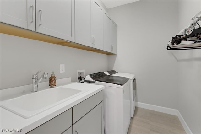 laundry area with sink, separate washer and dryer, and cabinets