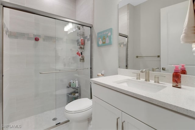 bathroom featuring toilet, an enclosed shower, and vanity