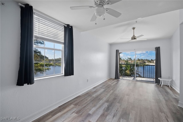 unfurnished room featuring ceiling fan, a water view, and light hardwood / wood-style floors