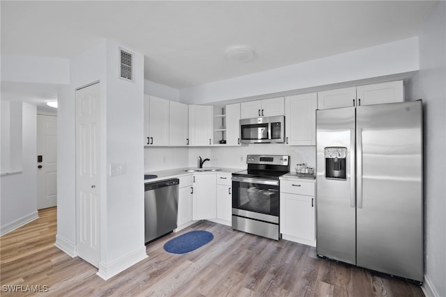 kitchen with white cabinets, stainless steel appliances, sink, and light hardwood / wood-style flooring