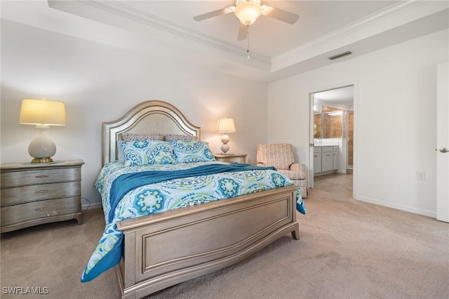 carpeted bedroom featuring a tray ceiling, connected bathroom, ceiling fan, and crown molding