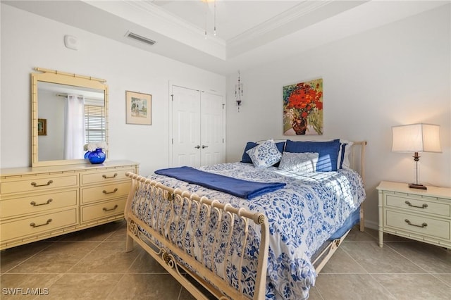 tiled bedroom featuring a tray ceiling, a closet, and crown molding