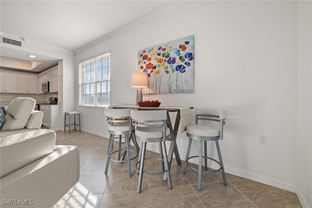 dining room with light tile patterned floors and crown molding