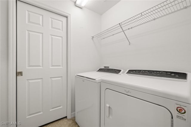 clothes washing area with washing machine and dryer and light tile patterned floors