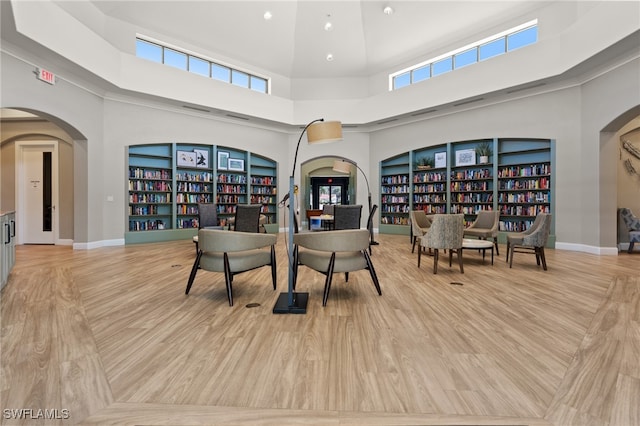 dining area with light wood-type flooring, a towering ceiling, and plenty of natural light