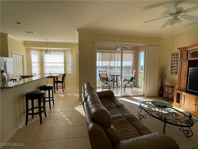 living room featuring ceiling fan with notable chandelier, light tile patterned flooring, and crown molding