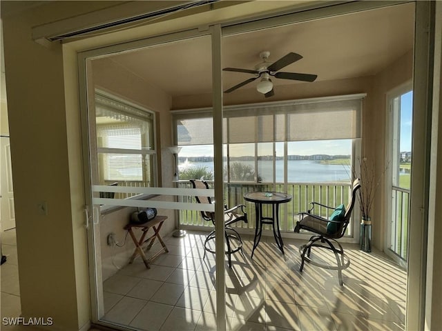 sunroom / solarium featuring ceiling fan and a water view