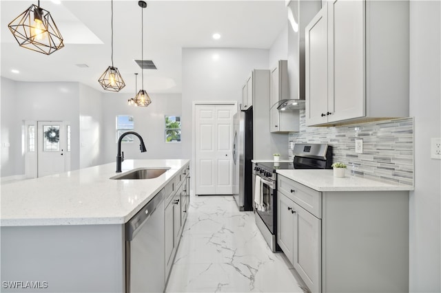 kitchen featuring a center island with sink, sink, light stone countertops, appliances with stainless steel finishes, and decorative light fixtures