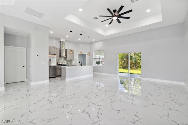 unfurnished living room with sink, ceiling fan, and a raised ceiling