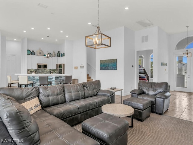 tiled living room featuring a notable chandelier and a towering ceiling