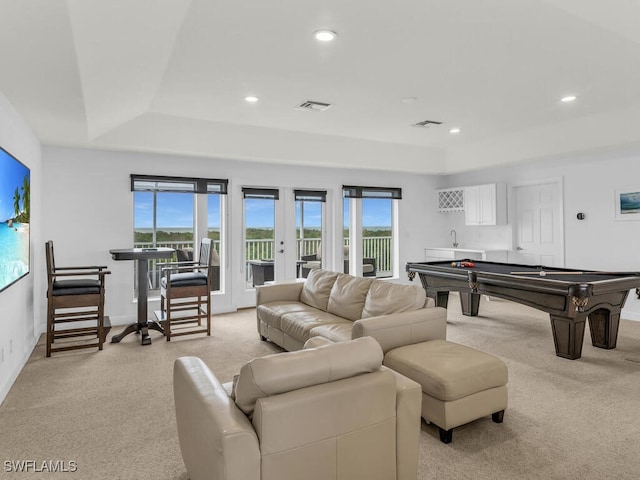 rec room with french doors, a raised ceiling, and light colored carpet