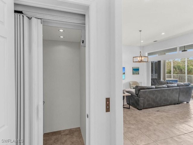 hall featuring a chandelier, elevator, and light tile patterned floors