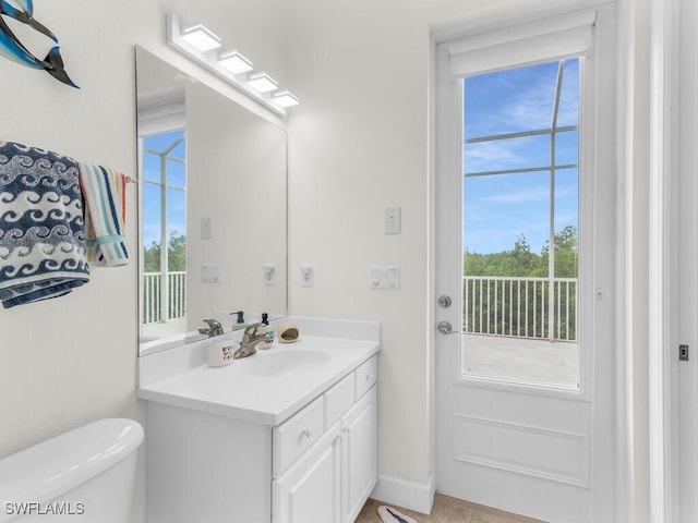 bathroom with toilet, vanity, and a wealth of natural light