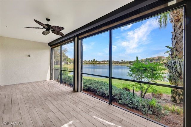 unfurnished sunroom featuring a water view and ceiling fan