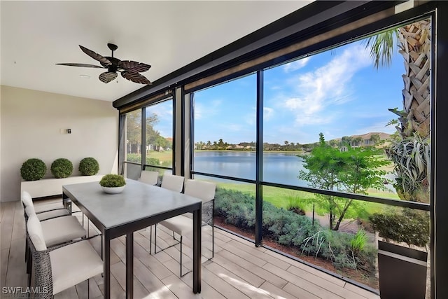 sunroom with a water view and ceiling fan