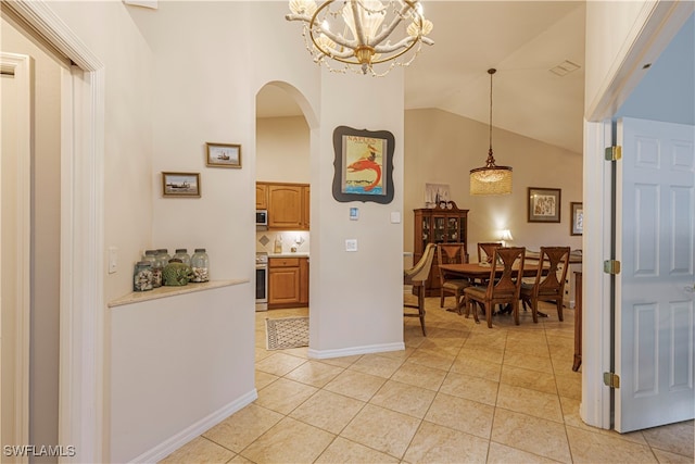 hallway featuring an inviting chandelier, lofted ceiling, and light tile patterned floors