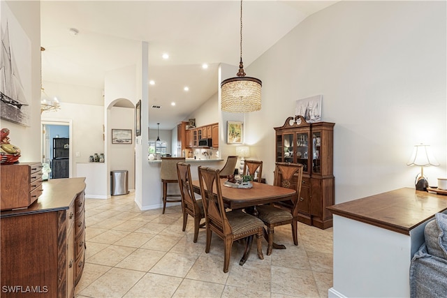 dining area with lofted ceiling, an inviting chandelier, and light tile patterned floors