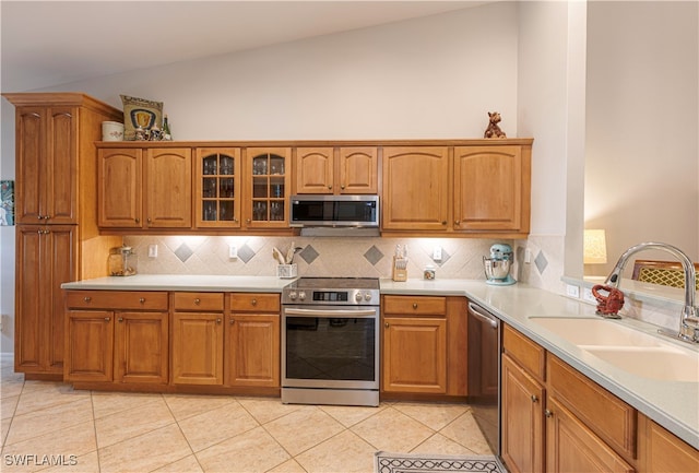 kitchen with sink, vaulted ceiling, appliances with stainless steel finishes, and light tile patterned floors