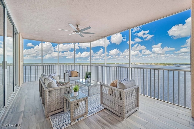 sunroom / solarium featuring a water view and ceiling fan