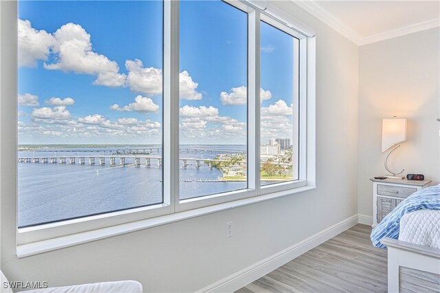 bedroom with crown molding, a water view, and wood-type flooring