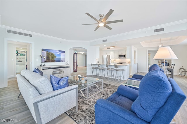 living room with crown molding, light wood-type flooring, and ceiling fan