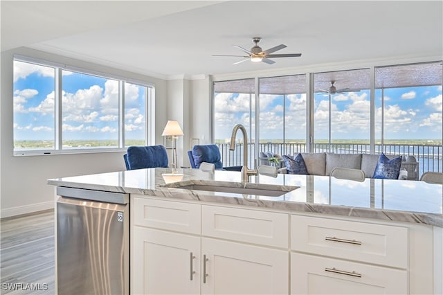 kitchen with sink, dishwasher, white cabinets, and light stone counters