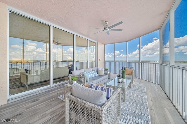 sunroom / solarium featuring a water view and ceiling fan