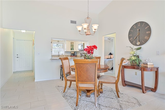 tiled dining room with sink, a notable chandelier, and high vaulted ceiling