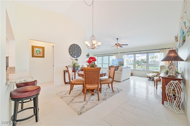 tiled dining space with high vaulted ceiling and ceiling fan with notable chandelier