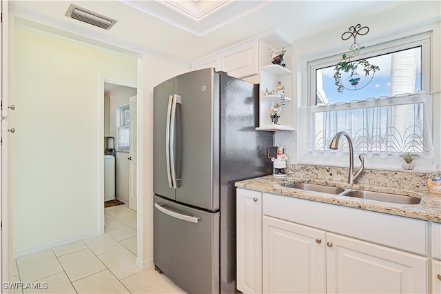 kitchen with white cabinetry, stainless steel refrigerator, sink, and decorative light fixtures