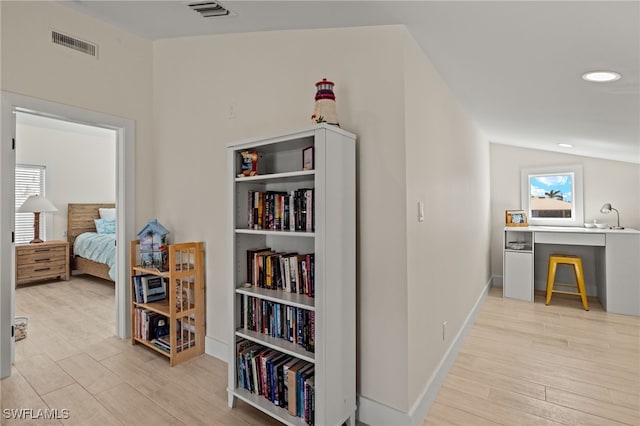 hall with light hardwood / wood-style floors and vaulted ceiling