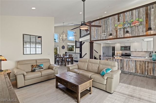 living room with ceiling fan with notable chandelier, lofted ceiling, and sink