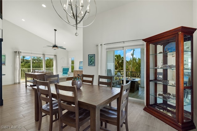 dining space featuring ceiling fan with notable chandelier, light hardwood / wood-style floors, and high vaulted ceiling